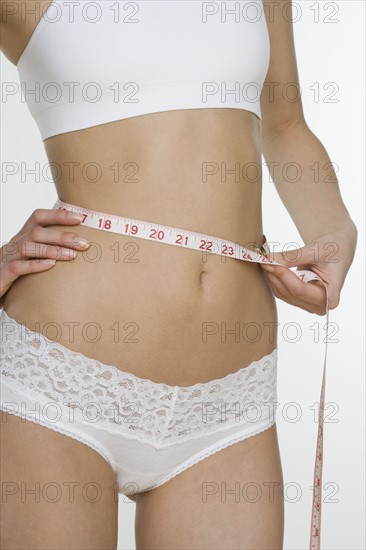 Woman in underwear measuring waist.