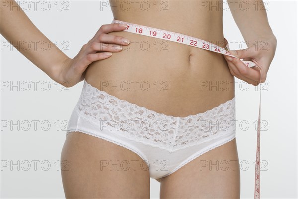 Woman in underwear measuring waist.