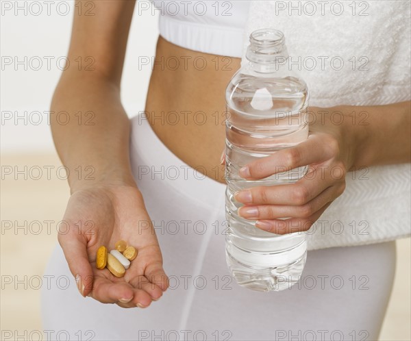 Close up of woman holding vitamins and bottle of water.