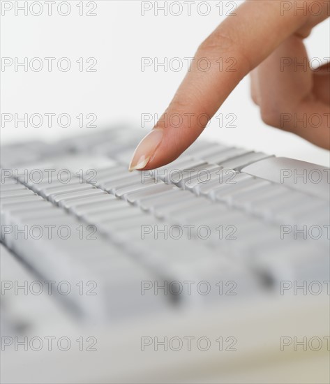 Close up of woman's finger over computer keyboard.