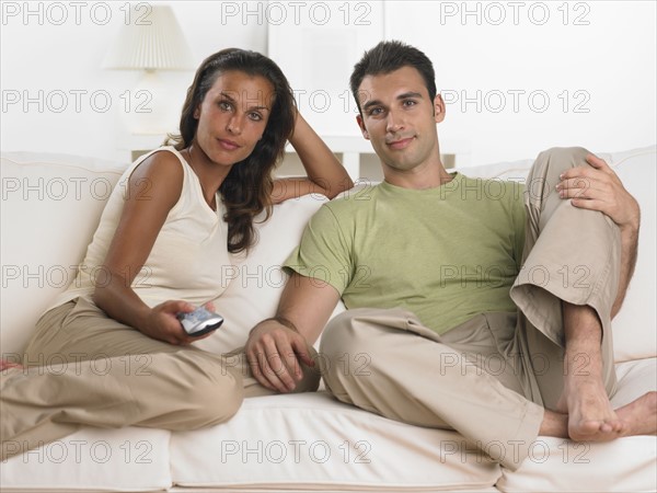 Couple sitting on sofa watching television.