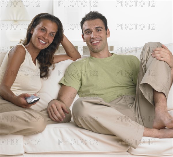 Couple sitting on sofa watching television.