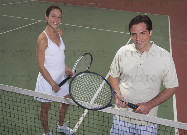 Couple smiling on tennis court.