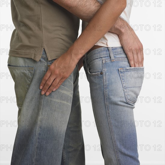 Couple hugging with man's hand in woman's back pocket.