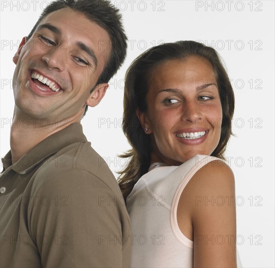 Couple smiling and standing back to back.