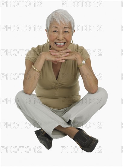 Studio shot of senior woman sitting cross-legged.