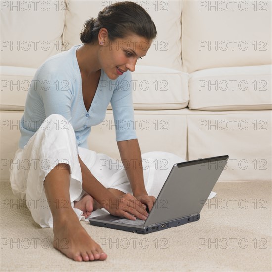 Woman using laptop on floor.