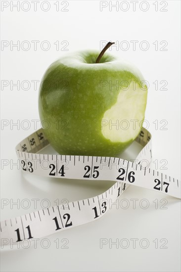Apple with bite taken out and tape measure.