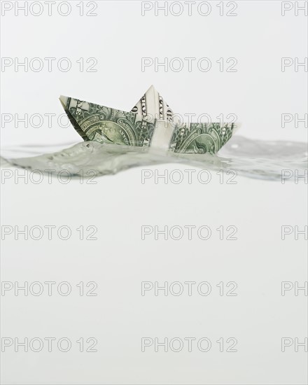 Boat made of US dollar floating on water.
