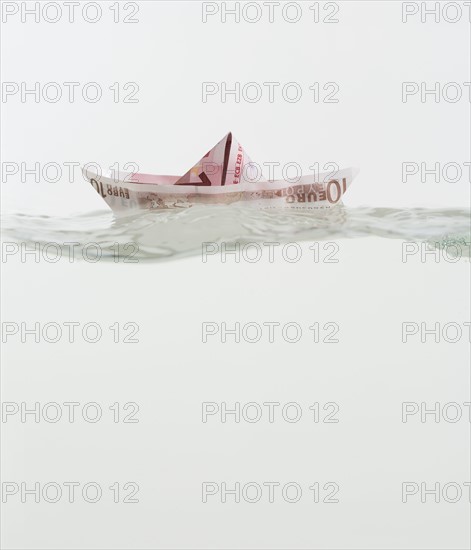 Boat made of paper money floating on water.