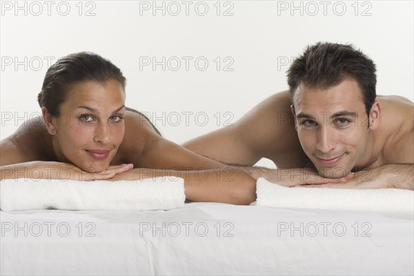 Couple laying next to each other and leaning on towels.