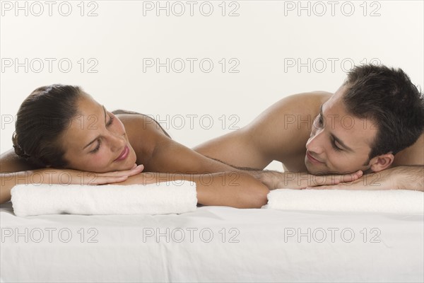 Couple laying next to each other and leaning on towels.