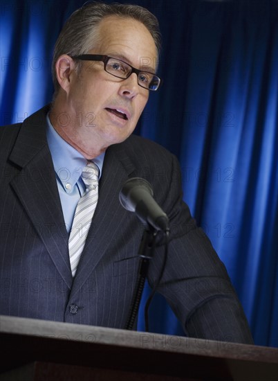 Close up of businessman speaking at podium.