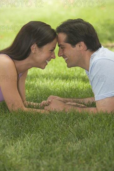 Couple touching foreheads and smiling in grass.