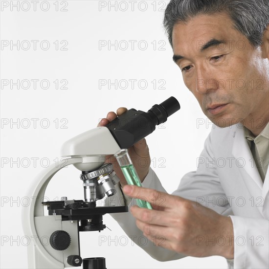 Man with vial of fluid and microscope.