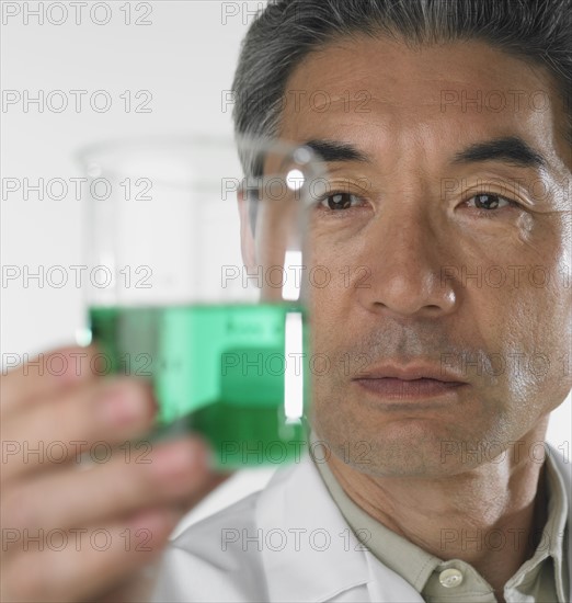 Man looking at beaker of fluid.