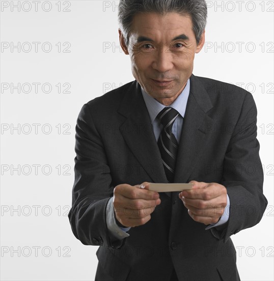 Senior Asian businessman offering business card.