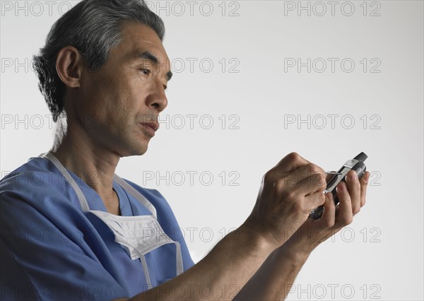 Studio shot of male doctor using PDA.