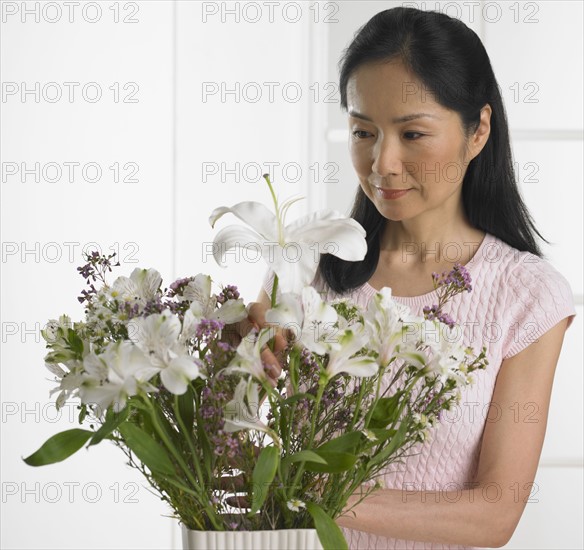 Woman arranging bouquet of flowers.