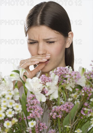 Woman about to sneeze and holding flowers.