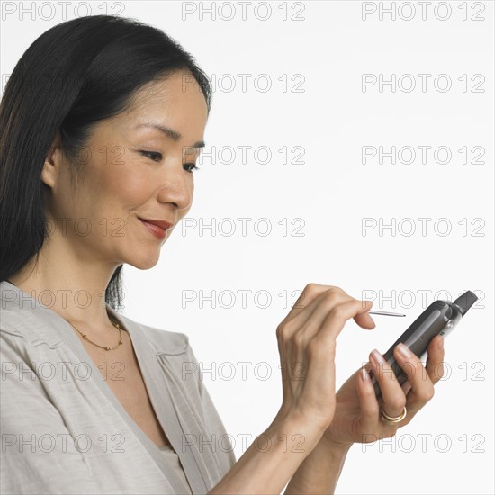 Studio shot of Asian woman using PDA.