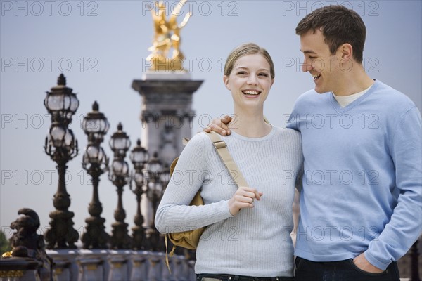 Couple smiling with golden statue in background.