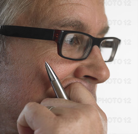 Close up of man holding pen and leaning on hand.