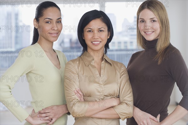 Three women smiling indoors.