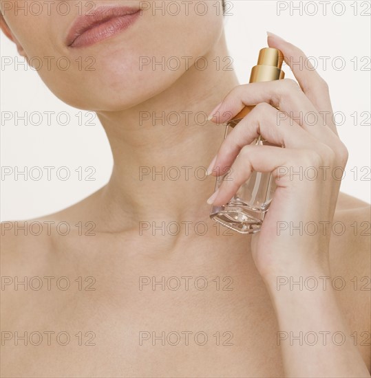 Woman spraying perfume on neck.