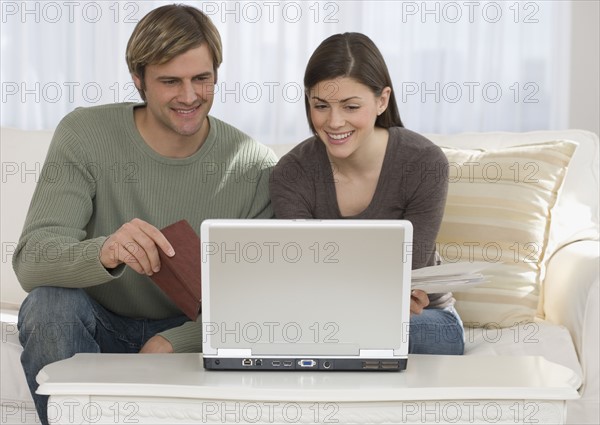 Couple paying bills on laptop.