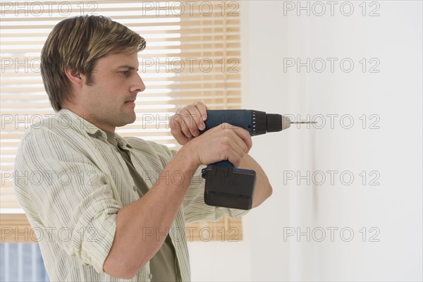 Man drilling hole in wall.