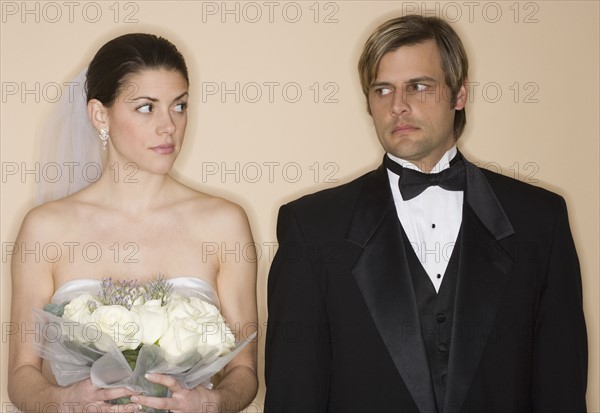 Angry bride and groom looking at each other.