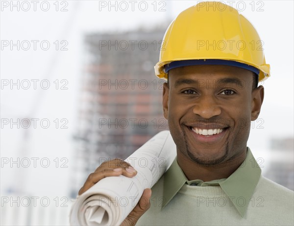 Portrait of man in hard hat holding blueprints.