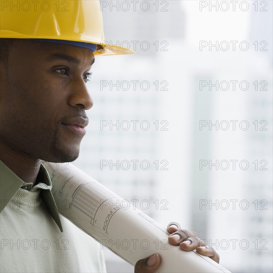 Man in hard hat holding blueprints.