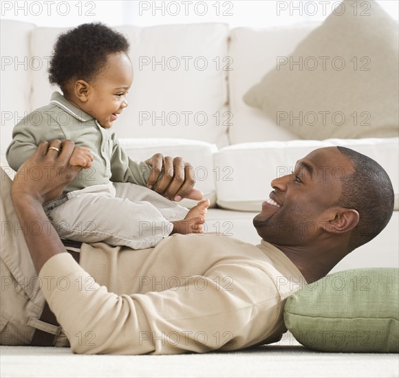 Father playing with baby on floor.