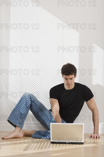 Man looking at laptop on floor.