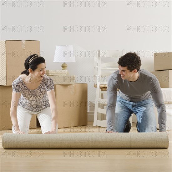 Couple unrolling rug in new house.