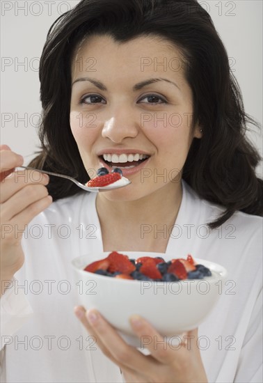 Woman eating bowl of fruit.