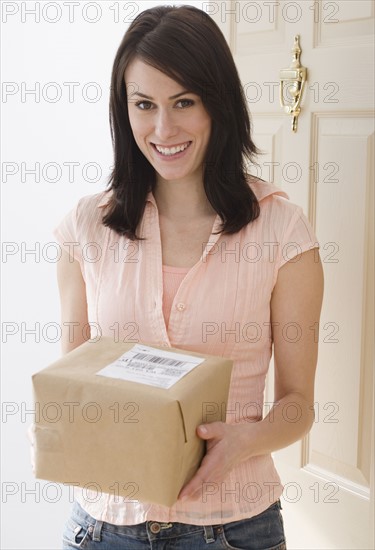 Portrait of woman holding package in doorway.