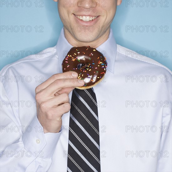 Businessman eating frosted donut.