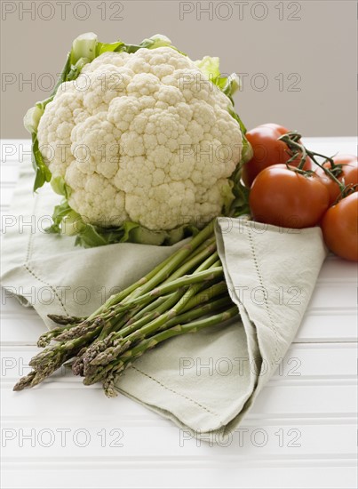 Cauliflower, tomatoes and asparagus on table.