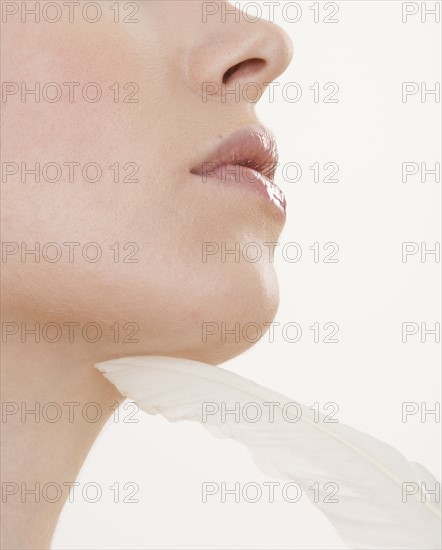Feather touching woman’s chin.
