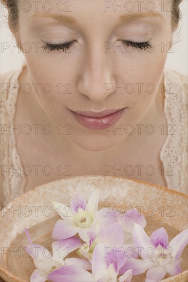 Woman smelling aromatherapy bowl with flowers.