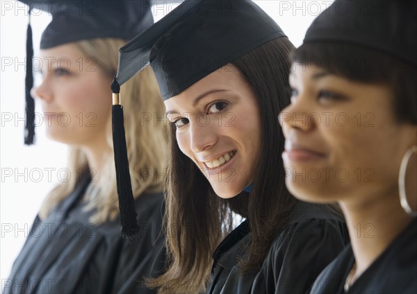 Multi-ethnic women wearing graduation cap and gown.