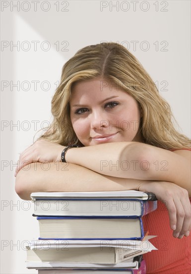 Woman leaning on stack of books.