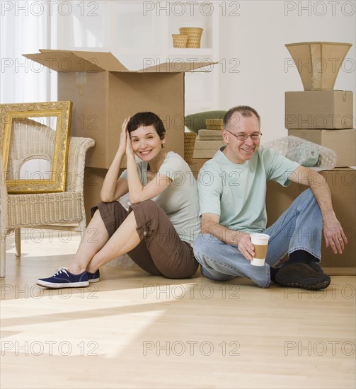 Couple on floor next to moving boxes.