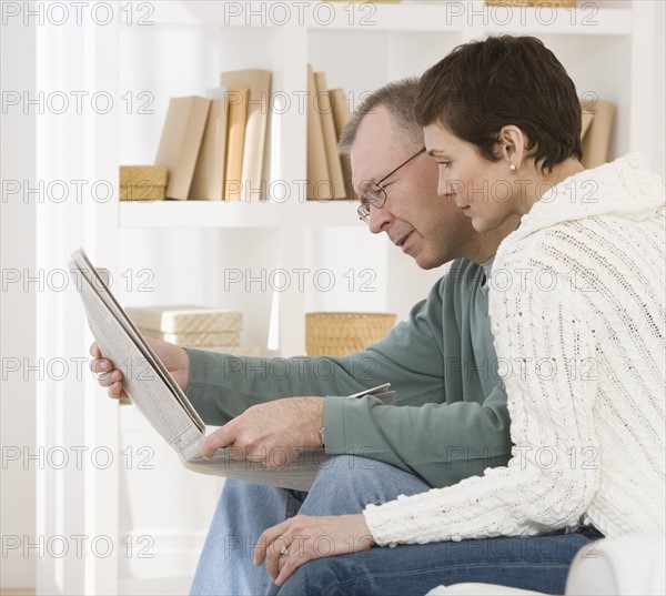 Couple reading newspaper.