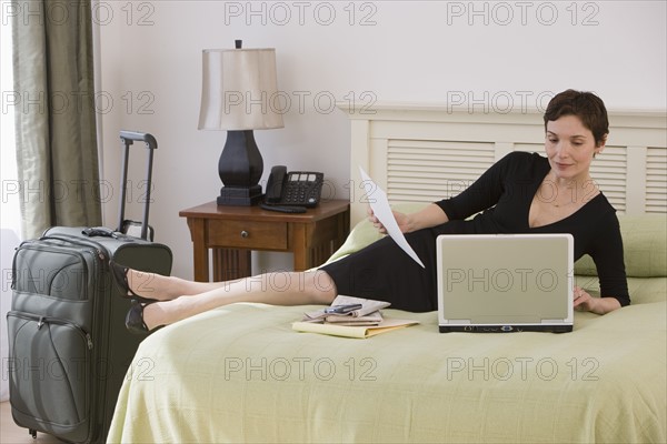 Businesswoman working on bed in hotel room.