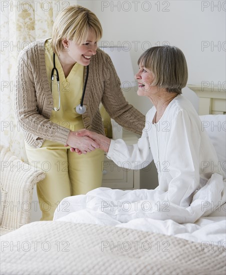 Nurse helping senior woman out of bed.