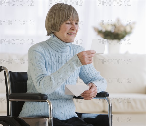 Senior woman in wheelchair reading letter.